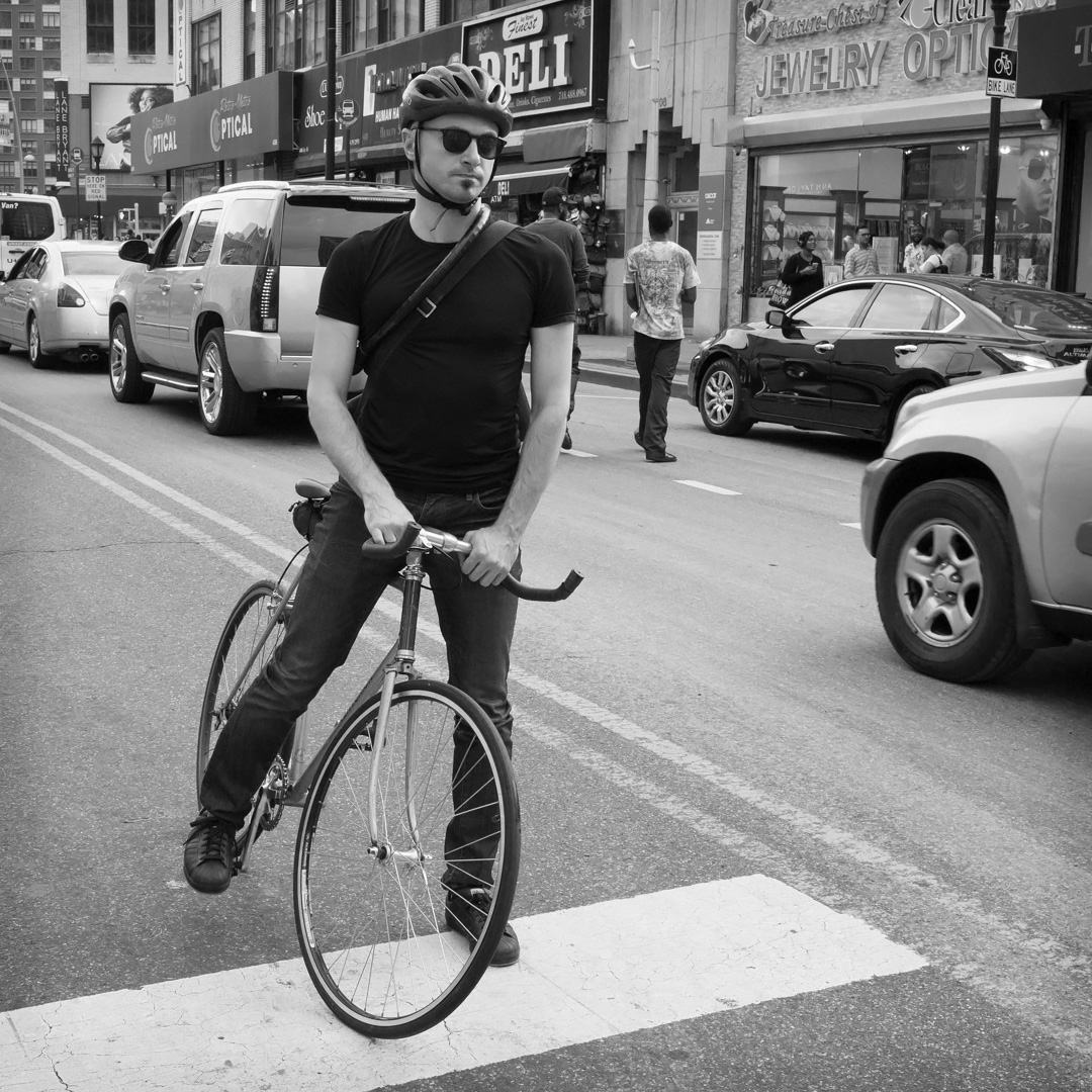 Photo: man on a bike, stopped at an intersection.